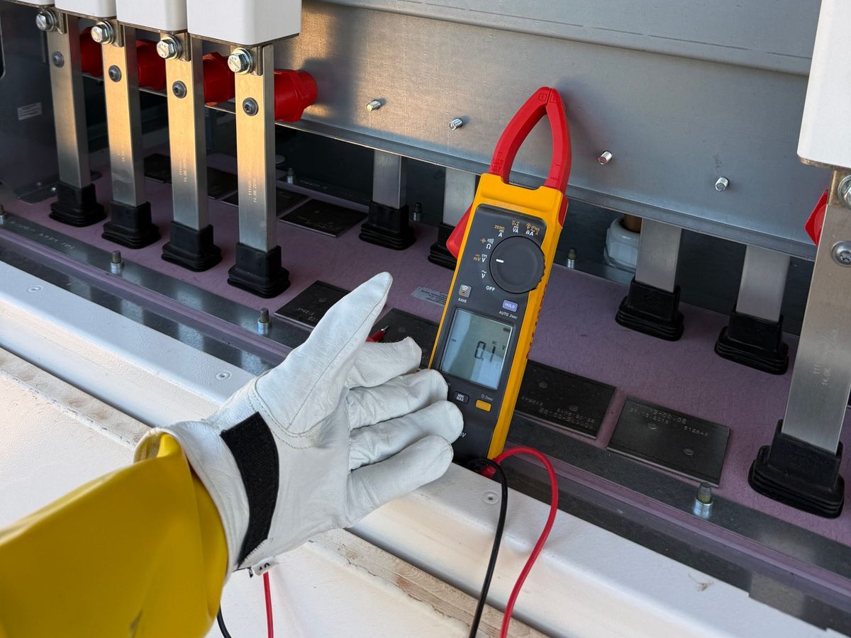 Electrician testing switchgear with a clamp meter on site